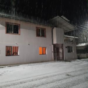 een wit gebouw met sneeuw op de grond bij CASA IZA in Băile Herculane