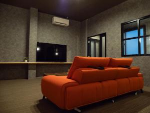 an orange couch sitting in a living room at 欒裏町ouchi uramachi in Matsumoto