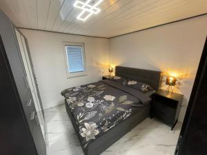 a small bedroom with a bed and two lamps at Second home apartment - gold in Kustići