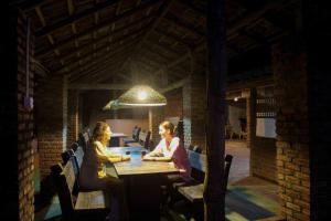 卡卢特勒Hotel Coconut Bay的两名女子坐在建筑物内的木桌旁。