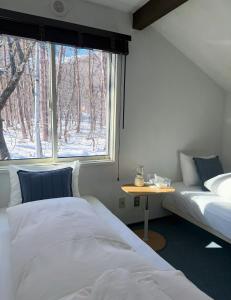 a bedroom with two beds and a window at Sugi Lodge in Hakuba