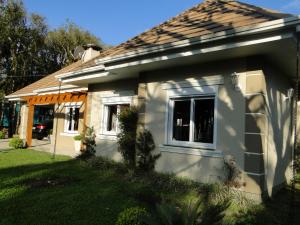 a small white house with a window in a yard at Casa Ari Candiago Gramado in Gramado