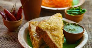 a plate of food with a sandwich and dipping sauce at Hotel Emerald Suites By Aura in Noida