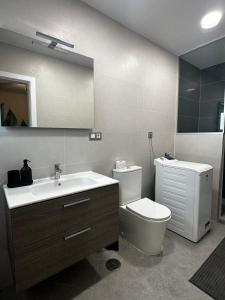 een badkamer met een wastafel, een toilet en een spiegel bij Arguineguín Heart in La Playa de Arguineguín