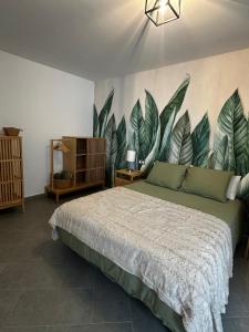 een slaapkamer met een bed met een muurschildering van bladeren aan de muur bij Arguineguín Heart in La Playa de Arguineguín
