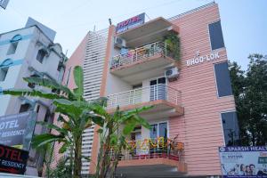 a pink building with a balcony in a city at AeroStay Comfort Inn - Near Ranchi Airport in Rānchī