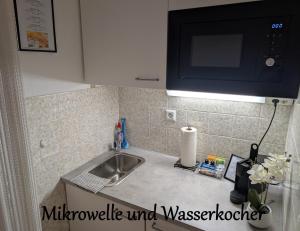 een aanrecht met een spoelbak en een magnetron bij Apartment "Waldrand" mit Balkon und Pool - Renoviert 2026 in Bad Essen +13 foto's