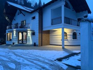 a house in the snow at night at Pensiunea Seraris in Voineasa