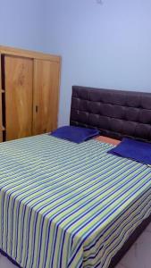 a bed with a blue and white striped blanket at Apparemment 2 chambres- Lemba Salongo in Kinshasa