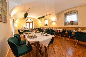 ein Esszimmer mit Tischen und grünen Stühlen in der Unterkunft Albergo Locanda Mezzosoldo in Mortaso