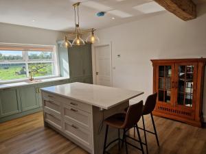 a kitchen with a white counter and two stools at The Lake House, cong in Cong