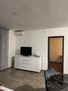 a white living room with a tv and a table at Apartman Lapaž 14 in Toplice Sveti Martin