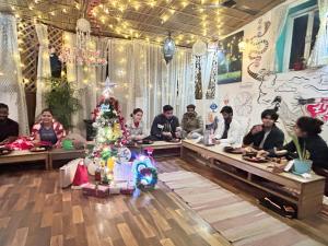 een groep mensen die aan tafel zitten in een kamer met een kerstboom bij The Pink Chapter Hostel, Jaipur in Jaipur +56 foto's