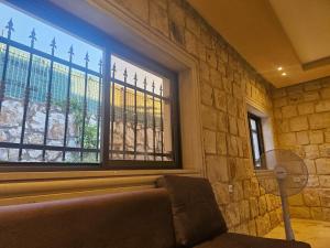 a living room with a couch and two windows at شالية بيتي in El Hoûé