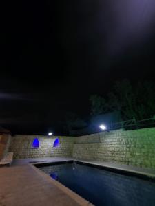 a swimming pool at night with blue lights at شالية بيتي in El Hoûé