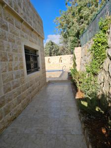 a sidewalk next to a brick wall with a window at شالية بيتي in El Hoûé
