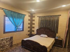 a bedroom with a bed and a window with blue curtains at شالية بيتي in El Hoûé