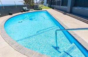 a large swimming pool with blue water at Dookes Apartment in Umdloti