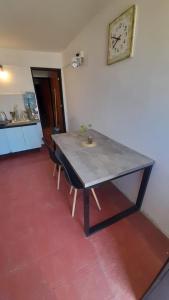 een tafel met twee stoelen en een klok aan de muur bij Apartamento Cosquin a metros del centro in Cosquín +3 foto's