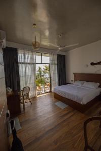a bedroom with a bed and a large window at Surftunnel Beach Resort in Weligama