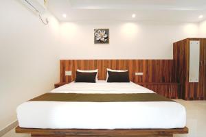 a bedroom with a large bed with a wooden headboard at Estoria Hotel and Resort in Mysore