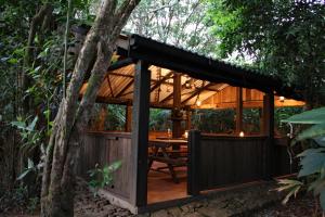 a wooden pavilion with a table in a forest at The Trogon Knuckles in Rangala