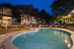 a swimming pool in a park at night at The Aralia in Dehradun