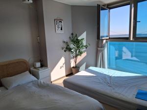 een slaapkamer met twee bedden en een groot raam bij Gwangan cozy in Kwangan-dong
