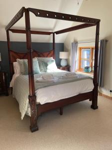 a bedroom with a wooden canopy bed with white sheets at Barn Cottage in Binton
