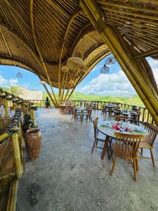 a restaurant with tables and chairs and a roof at Green Poya - Luxury Eco Bambu Resort in South Lombok in Selong Belanak