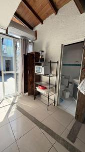 a room with a kitchen with a microwave on a shelf at Refúgio do Descanso in Florianópolis