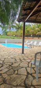 a stone patio with chairs and a swimming pool at Refúgio GRUPOS com piscina, churrasqueiras 38 min Águas Claras Brasília in Brasília +30 photos
