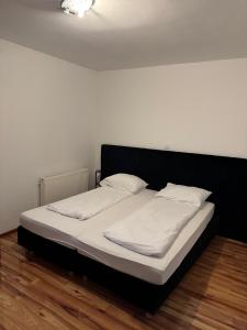 a bed with a black headboard and white sheets and pillows at Soba Lapaž in Toplice Sveti Martin