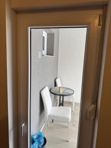 a glass table and white chairs in a room at Soba Lapaž in Toplice Sveti Martin