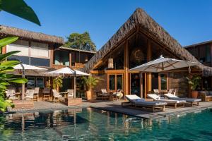 a resort with a swimming pool with chairs and umbrellas at Aketá Hotel Boutique in Trancoso