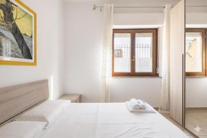een witte slaapkamer met een bed en een raam bij Dimoras Bellissimo Appartamento Centrocittà in Olbia