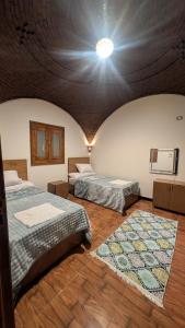 two beds in a room with a ceiling at The Village House with Private Garden - Four Bedroom Nubian Home on Luxor West Bank in Luxor