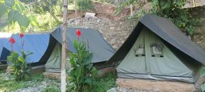 two tents sitting next to a stone wall at Kinara Camping in Kailāna