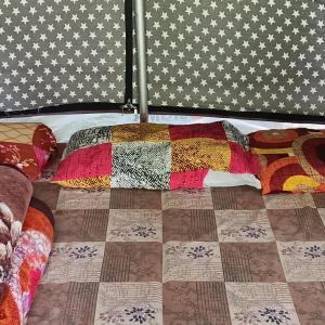 a bed with colorful quilts on top of it at Kinara Camping in Kailāna