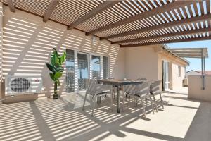 een patio met een tafel en stoelen en verwarming bij EnVi Apartments in Murter