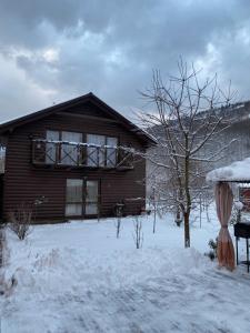 a wooden house with a balcony in the snow at Brendushka in Rakhiv