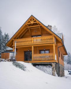 een houten huis met een balkon bovenop de sneeuw bij Apartamenty na Soszowie, Wisła - widokowe miejsce z Balią & Prywatną Sauną, obok stoku narciarskiego i Bike Parku, dla max 16 osób in Wisła