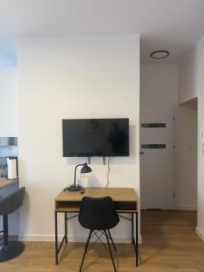 a desk with a chair and a television on a wall at MW 4A Apartament in Rzeszów