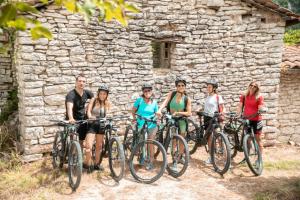 a group of people standing with bikes in front of a stone building at Libera Mente in Fabriano