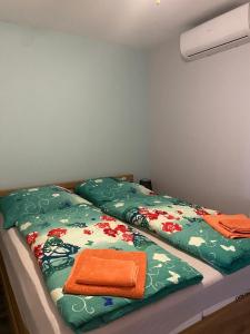 a bed with green sheets and an orange towel on it at Lakeview Apartment & Spa in Belosavci