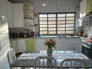 a kitchen with a table with a vase of flowers on it at Aconchego de mae - 5 min do Santuário e comércios - Casa completa in Aparecida