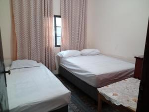 two beds in a small room with a window at Aconchego de mae - 5 min do Santuário e comércios - Casa completa in Aparecida