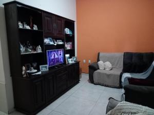 a living room with a tv and a chair at Aconchego de mae - 5 min do Santuário e comércios - Casa completa in Aparecida