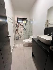 een badkamer met een wastafel, een toilet en een douche bij El Lago in Coronado +3 foto's