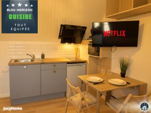 a kitchen with a table and a tv on the wall at Bleu Horizon in Berck-sur-Mer +17 photos